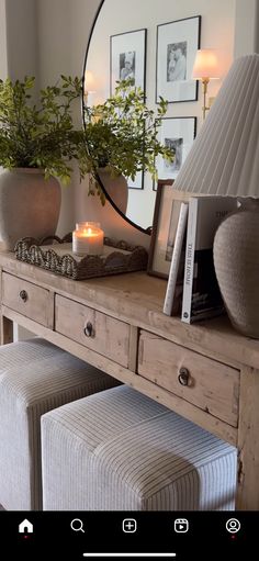 a wooden table topped with a mirror and two vases filled with plants