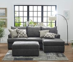 a living room with a large gray sectional couch and matching footstool in front of a window