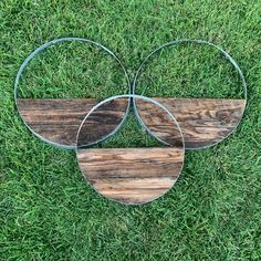 three metal and wood circles sitting in the grass