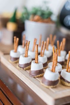 chocolate covered desserts with pretzel sticks on them are sitting on a wooden tray