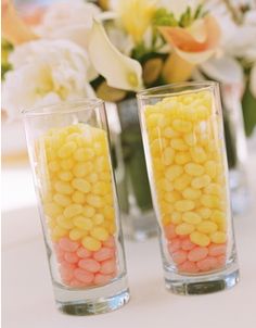 two vases filled with yellow and pink candy corn sitting on top of a table