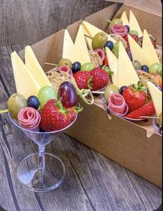 some fruit is sitting in a box on a table next to a wine glass and bag