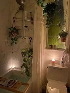 a bathroom with a toilet, bathtub and plants on the wall next to it