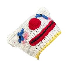 a white crocheted pillow with a red, yellow and blue design on it