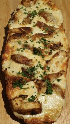 a cheesy pizza on a wooden surface with parsley sprinkled on top