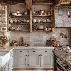 a kitchen filled with lots of white cabinets and wooden shelves next to a stove top oven