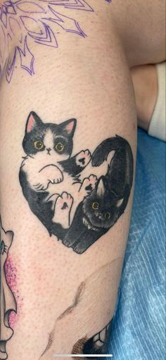 a cat tattoo on the leg of a woman's thigh, with two cats in it