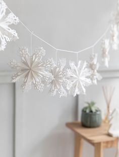 white snowflakes hanging from a string in a room with a table and chair