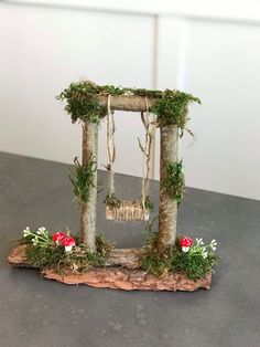 a small wooden frame with moss and flowers on the side, sitting on a table