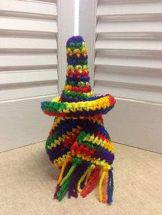 a multicolored knitted hat sitting on top of a white counter next to shutters