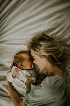 a woman laying on top of a bed holding a baby