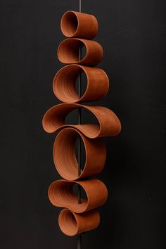 a sculpture made out of brown paper on a black background with circles hanging from it's sides