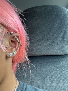 a woman with pink hair and piercings on her ears is sitting in a car