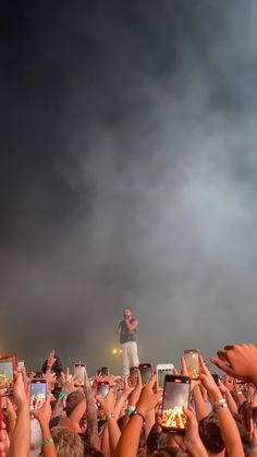 a man standing on top of a stage surrounded by people holding up their cell phones