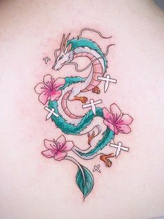 the back of a woman's shoulder with flowers and dragon tattoos on her left side