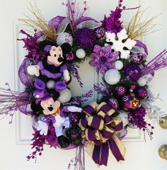 a purple and gold mickey mouse wreath on a white door with ornaments around the wreath