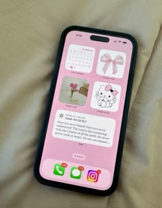 a pink iphone with pictures on it sitting on top of a white bed sheet in front of a pillow