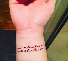 a woman's wrist tattoo with the words inside exhale written on her left hand