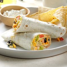 two burritos on a plate with salsa and tortilla chips