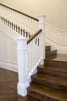 a white staircase with wooden handrails and wood flooring