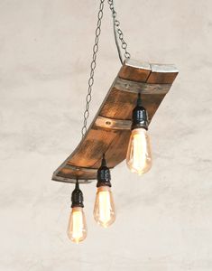 three light bulbs are hanging from a wooden plank chandelier with chains attached to it