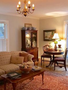 a living room filled with furniture and a chandelier hanging from the ceiling over a table