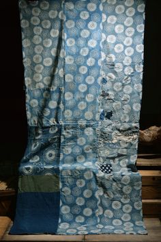 a blue and white blanket sitting on top of a wooden floor next to a pile of wood