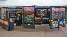 a group of paintings on display under a tent