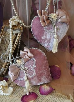 two heart shaped purses sitting on top of a table next to flowers and pearls