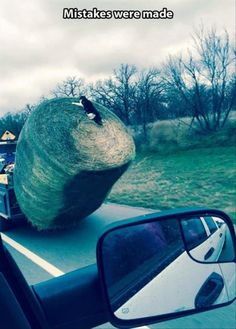 a large rock sitting on the side of a road next to a car's rear view mirror