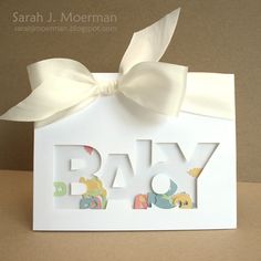 a card with the word baby on it and a white bow tied around its neck