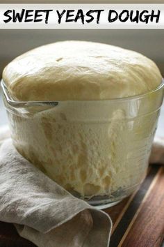 a glass bowl filled with bread sitting on top of a wooden table next to a napkin