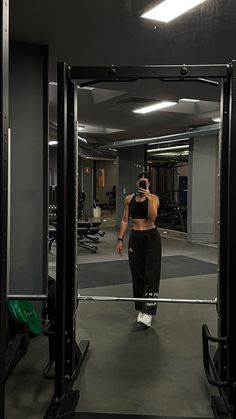 a woman is walking through the gym with her cell phone up to her ear and looking at herself in the mirror