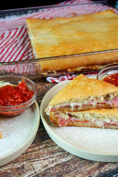 a sandwich cut in half sitting on top of plates next to a bowl of salsa