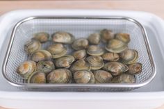 a basket filled with clams sitting on top of a wooden table