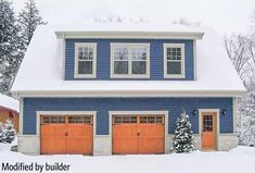 a blue house with orange garage doors in the snow