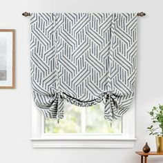 a window with a blue and white patterned roman blind in front of a potted plant