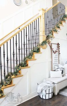 a staircase decorated for christmas with garland and lights on the bannister railings