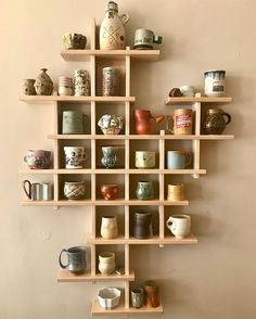 a wall shelf filled with lots of cups and mugs on top of wooden shelves