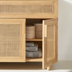 a wooden cabinet with baskets and towels in it