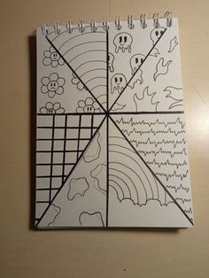 a spiral notebook with drawings on it sitting on a table