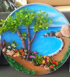 a plate that is decorated with flowers and trees on the side of a couch next to a remote control