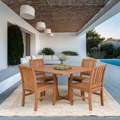 an outdoor dining area with wooden chairs and a round table next to a swimming pool