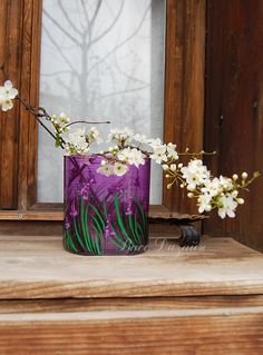 a purple vase with white flowers in it on a window sill next to a wooden door