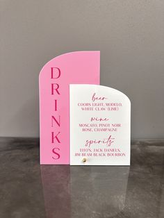 a pink drink menu card sitting on top of a table