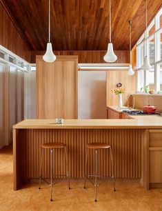 two stools are sitting at the center of this kitchen island in an open floor plan