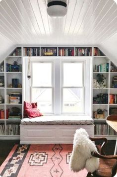 an attic bedroom with bookshelves full of books and a window seat in the corner