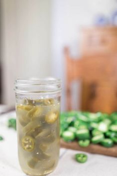 a jar filled with pickles sitting on top of a table next to a cutting board