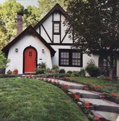 a house with steps leading up to it and flowers in the front yard, along with landscaping