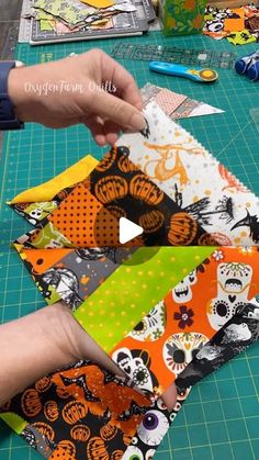 someone is cutting out halloween fabric on a table